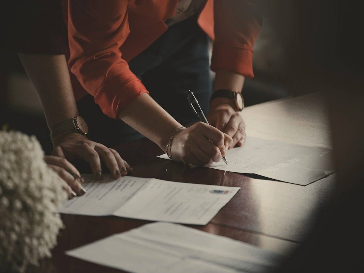 Hands signing paperwork at a table