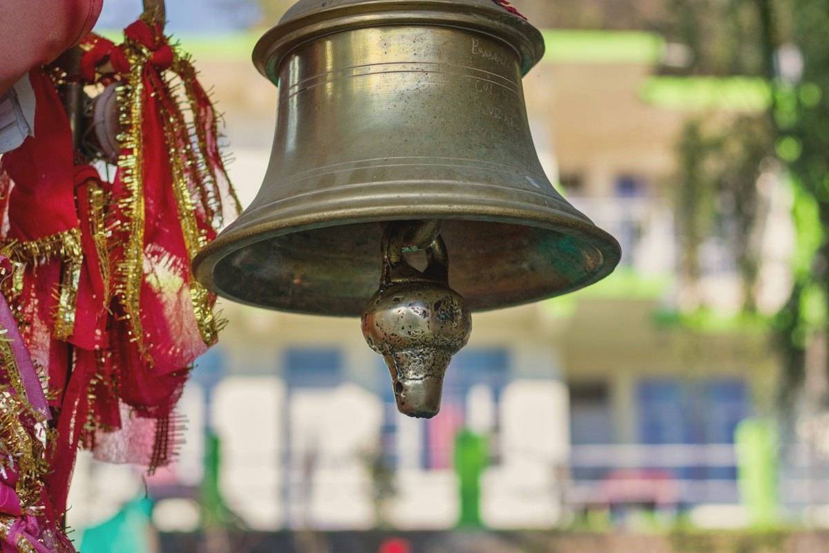 A brass temple bell hanging with red sacred threads