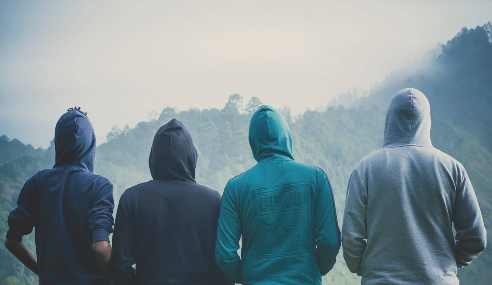 Four friends in hoodies looking out at misty mountains