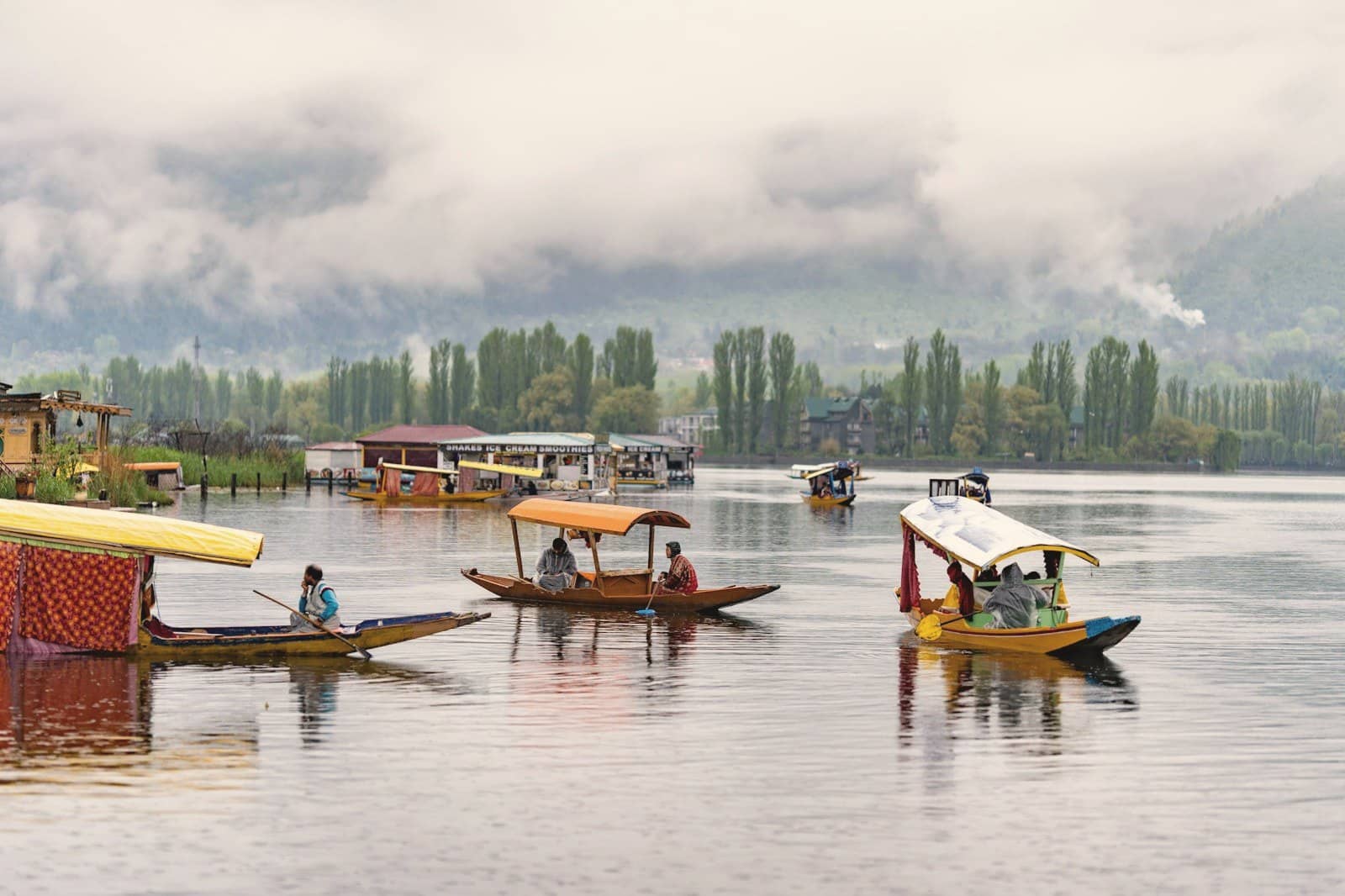 Shikara boats on Dal Lake in Srinagar with houseboats and misty hills