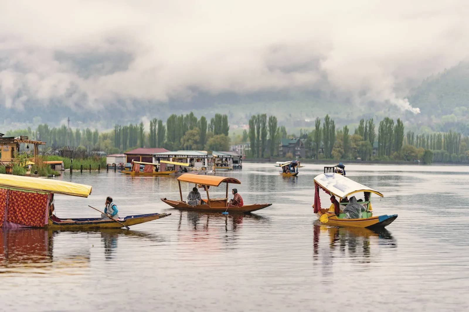 Shikara boats on Dal Lake in Srinagar with houseboats and misty hills